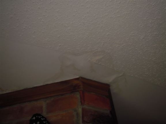 Here you can see a water-damaged ceiling near a chimney  most likely due to a flashing issue.