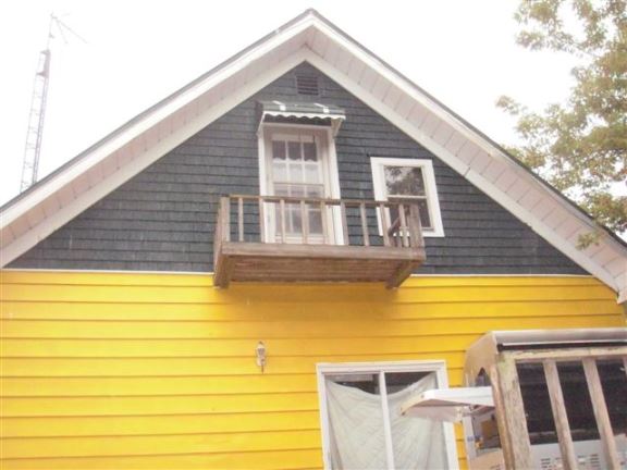 This dangerous balcony has little support and a very low safety railing. It is an accident waiting to happen.