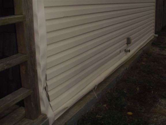 This wall was not extended past the foundation, causing water to run under the sill and rot out the base of the wall. The siding is now bowing out.