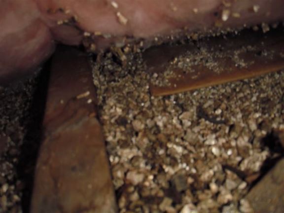 This vermiculite insulation in an upper attic was hidden under fiberglass insulation and could contain asbestos.